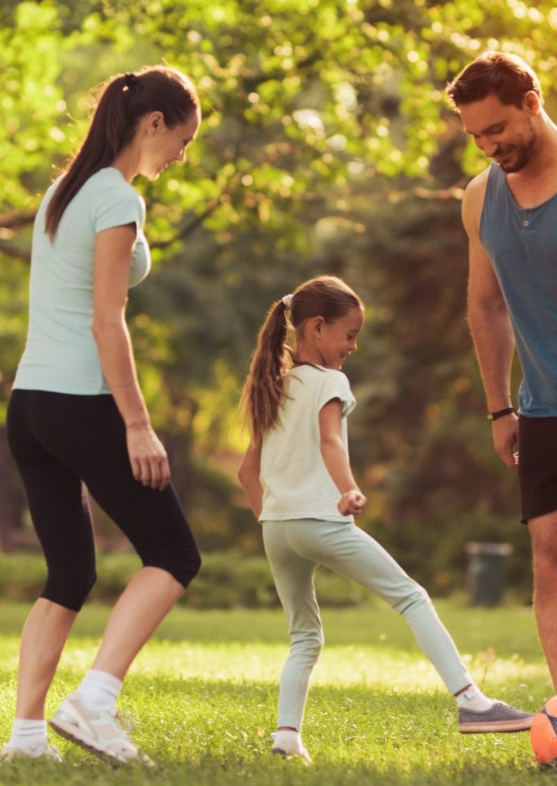 Parents and Daughter Play Football. Guys Smile.